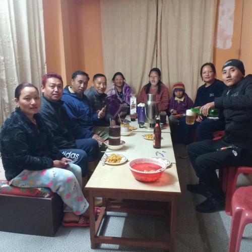 un gruppo di persone seduti intorno a un tavolo di Khangri Homestay a Rongli