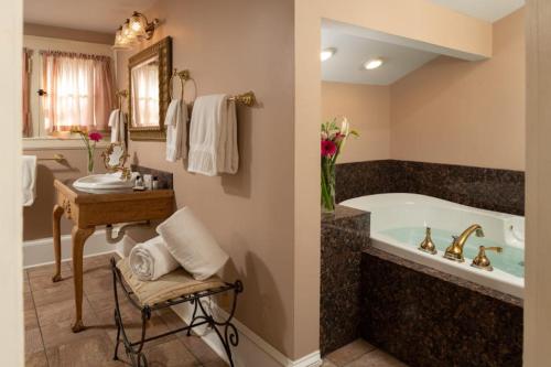 a bathroom with a tub and a table and a sink at Albemarle Inn - Asheville in Asheville