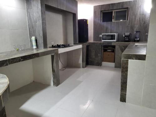 a large kitchen with a counter and a microwave at Casa alberca cerca de todo. zona pastora. cochera in Monterrey