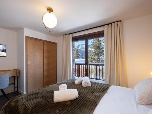 une chambre avec un grand lit avec des serviettes dessus dans l'établissement Appartement raffiné à Courchevel Moriond pour 8 personnes, proche pistes et commerces - FR-1-563-148, à Courchevel