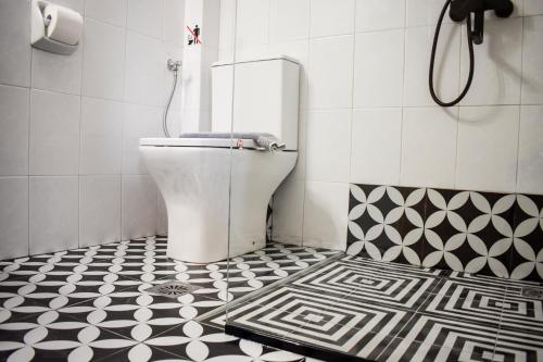 a bathroom with a toilet and a black and white tile floor at Hotel Kostis in Skiathos