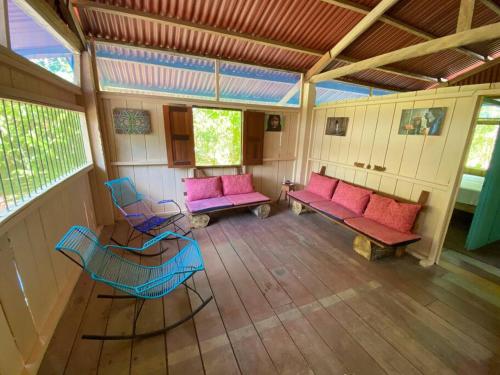 un porche cubierto con muebles de color rosa y azul en Casa en la selva con acceso al río - Casa Ikua, en Iquitos