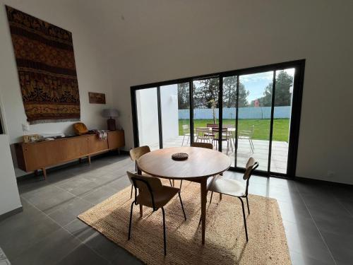 una sala da pranzo con tavolo e sedie e una grande finestra di Glen Ross, plage à moins de 10 min à pied a Névez