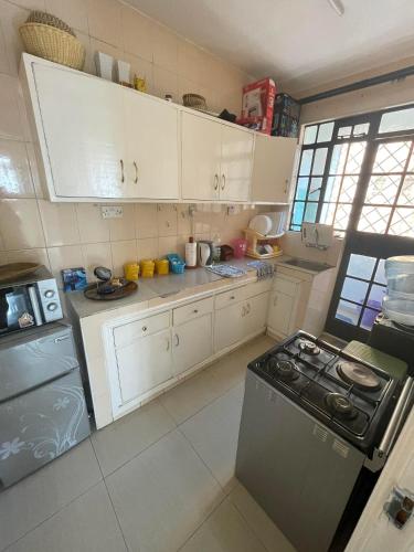 a kitchen with white cabinets and a stove top oven at Langata, Deliverance Church, Jamhuri Heights Apartments in Nairobi