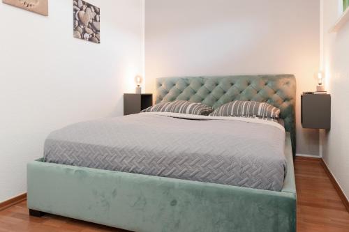 un letto con testiera blu trapuntata in una camera da letto di Prinzenhof Meerblicktraum a Grömitz