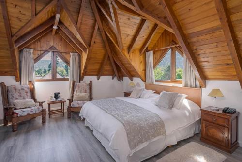 Un dormitorio con una cama grande en una habitación con techos de madera. en Le Chatelet en San Martín de los Andes
