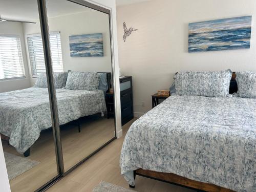 a bedroom with two beds and a mirror at Oceanside Getaway in Oceanside