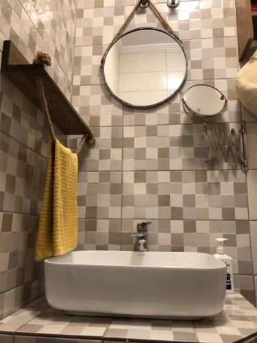 W łazience znajduje się biała umywalka i lustro. w obiekcie Lefkothea's central apartment w Salonikach
