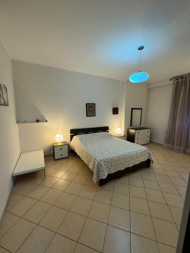een slaapkamer met een bed en twee tafels en een blauw licht bij 3 Bedrooms Apartment in Shkodër