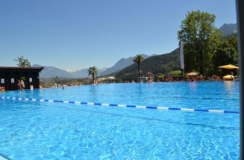 a swimming pool filled with blue water with mountains in the background at Appartement Ariane in Frastanz