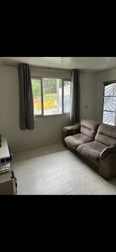uma sala de estar com um sofá castanho em frente a uma janela em Casa Inteira com Churrasqueira em Ponta Grossa