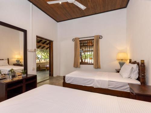 a bedroom with two beds and a mirror at Joe's Bungalow Yala in Kirinda