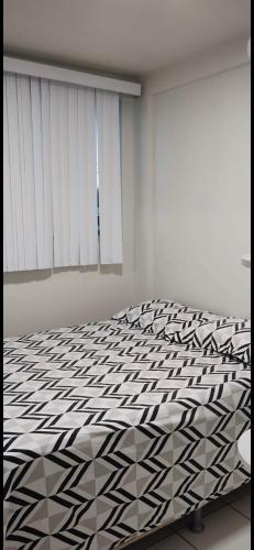 a bedroom with a bed with a black and white comforter at Apto para até 4 pessoas,ótima localização, área de lazer para crianças,conveniência e piscina in Petrolina