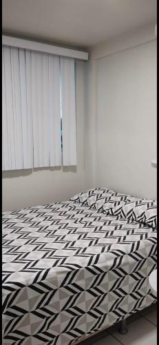 a bedroom with a bed with a black and white comforter at Apto para até 4 pessoas,com Wi-Fi,ótima localização, área de lazer com conveniência e piscina para criança in Petrolina