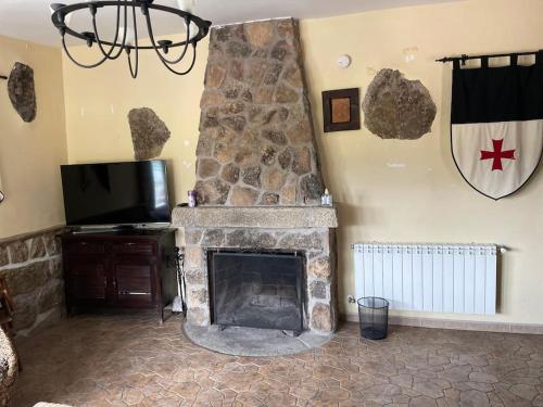 sala de estar con chimenea de piedra y TV en Picos Pardos CRA-AV-1088, en El Barraco