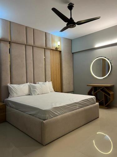 a bedroom with a large bed with a ceiling fan at Marigold Accommodations in Karachi