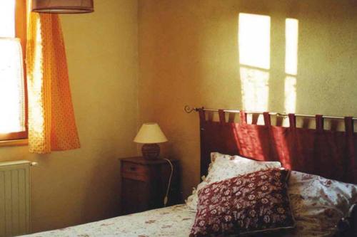 una camera con letto, lampada e finestra di Gîte La Grange Du Haut a Saint-Antoine