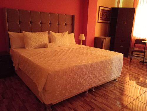 a bedroom with a large bed with a large headboard at Madison Suite in Tacna