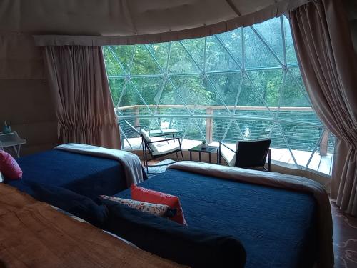 1 dormitorio con 2 camas y ventana grande en GlampOut Resort - Elk River en Sutton