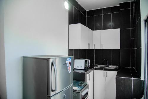 eine kleine Küche mit einem Kühlschrank und einer Mikrowelle in der Unterkunft CondoLind - Lomé 