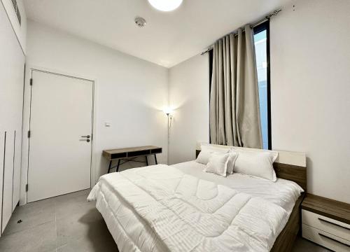 a white bedroom with a large bed and a window at Private Room in a Shared Apartment in Sharjah