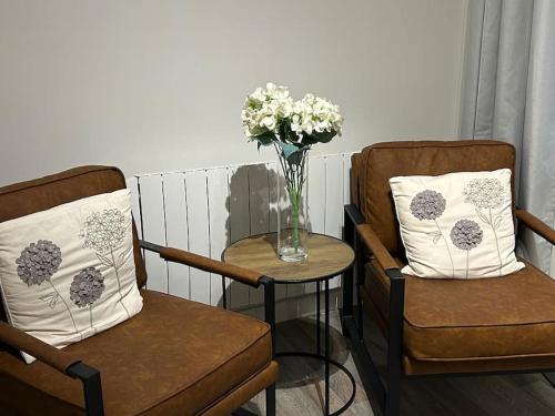 un jarrón de flores en una mesa junto a dos sillas en Modern 2 bedroom apartment - Neath Town centre, en Neath