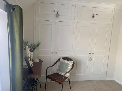 a room with a chair and white cabinets at Cosy cottage in Chard