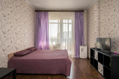 ノヴォシビルスクにあるApartments Freedom on Kirovaのベッドルーム1室(ベッド1台付)、紫色のカーテン付きの窓が備わります。