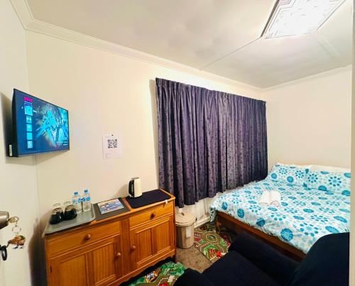 1 dormitorio con 1 cama y TV en la pared en Double bed room in Invercagill/5mini walk to city, en Invercargill