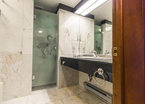 a bathroom with a sink and a shower with birds on the wall at Hôtel et Centre de Villégiature Lac Carling in Grenville-sur-la-Rouge