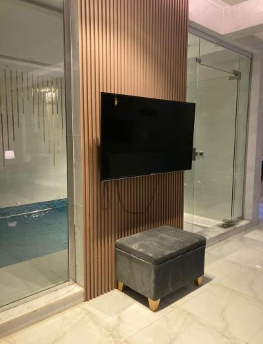 um quarto com uma televisão e um banco com uma televisão na parede em شاليه خاص vip الشقيق-الدرب em Ash Shuqayq