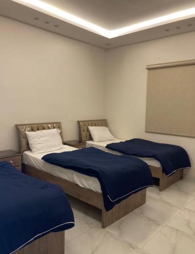 two beds in a room with blue blankets on them at شاليه خاص vip الشقيق-الدرب in Ash Shuqayq