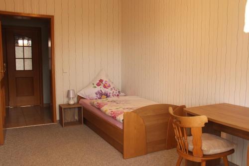 a small bedroom with a bed and a wooden table at Ferienwohnung Mietzner in Laubach