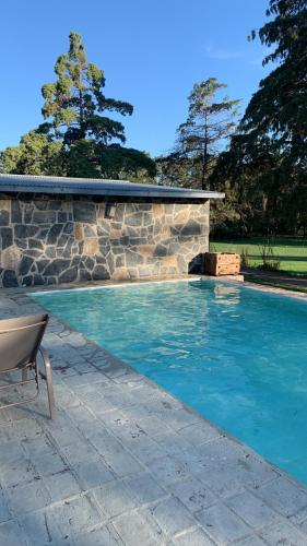 a swimming pool with a stone wall and blue water at Casa Falda del Carmen in Santa María