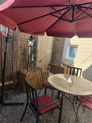 - une table et des chaises sous un parasol rouge sur la terrasse dans l'établissement Les hirondelles, à Arrest