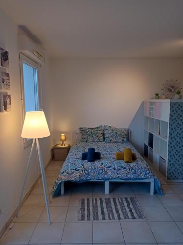 um quarto com uma cama e um candeeiro em Studio proche de la gare avec le calme des vignes. em Libourne