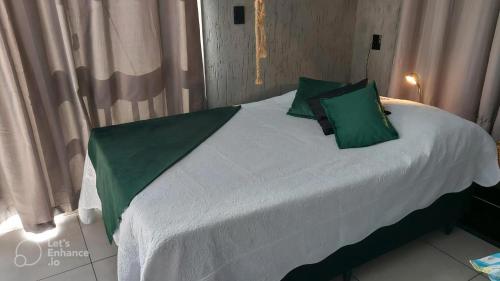 a bed with green pillows on it in a room at Recanto dos pássaros in Garibaldi