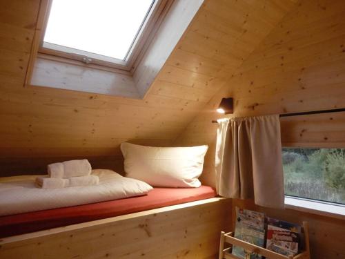 a bed in a wooden cabin with a window at Holiday apartment in Thuringia in Zierow