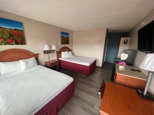 a hotel room with two beds and a flat screen tv at University Inn Chico in Chico