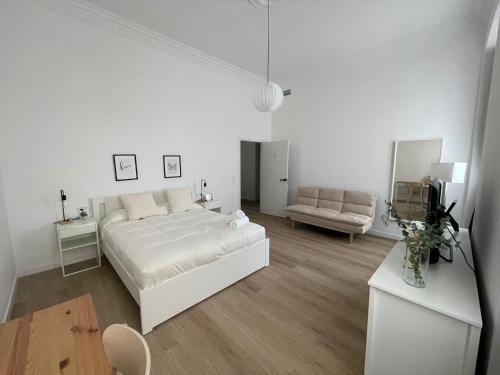 a white bedroom with a bed and a couch at Suites Larios in Málaga