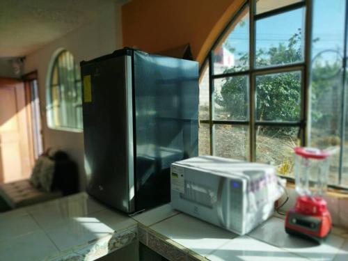 kuchenka mikrofalowa na blacie obok okna w obiekcie 3 Cuarto independiente individual Ambato w mieście Ambato