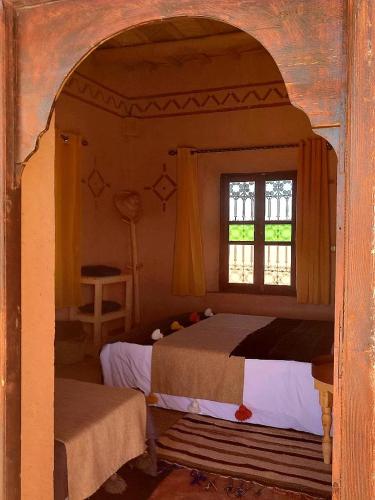 a bedroom with a bed and a window at Maison d'hôtes IZZA in Kalaat MGouna