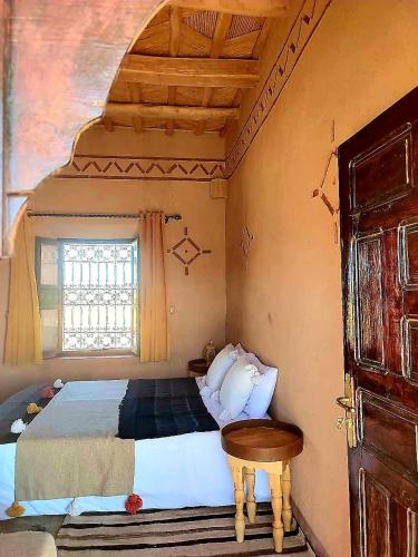 a bedroom with a bed and a window at Maison d'hôtes IZZA in Kalaat MGouna