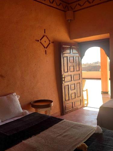 a bedroom with a door and a bed and a table at Maison d'hôtes IZZA in Kalaat MGouna