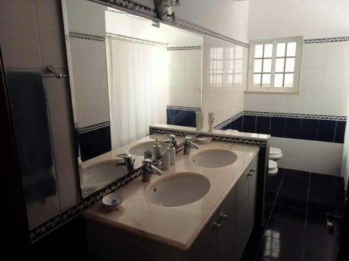 uma casa de banho com 2 lavatórios e um espelho grande em Moradia da Bananeira em Lagoa de Albufeira