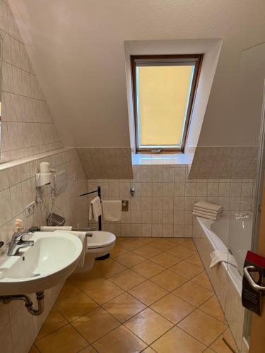 a bathroom with a sink and a toilet and a window at Annas Gästehaus in Hallerndorf