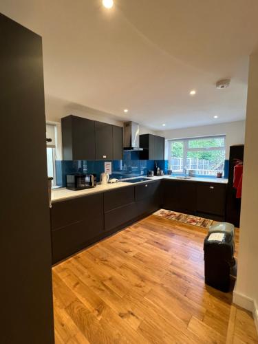 eine Küche mit schwarzen Schränken und Holzböden in der Unterkunft En-suites and Rooms Near Wembley Stadium in London