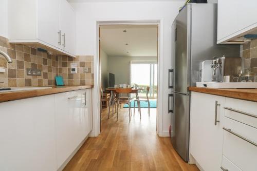a kitchen with white cabinets and a dining room at Rock Pool in Downderry