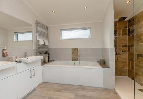 a bathroom with a tub and a sink and a shower at Loch Lomond Holiday Park in Inversnaid