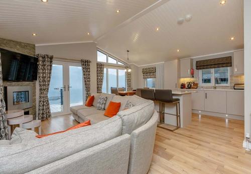 a living room with a large couch and a kitchen at Loch Lomond Holiday Park in Inversnaid